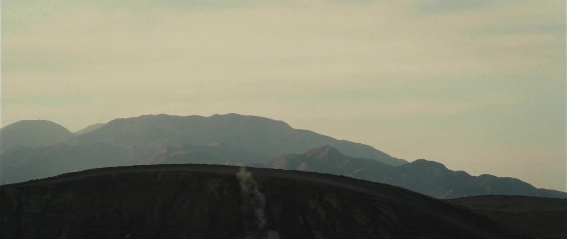 Rider jumps bike into air as they ride over dusty slope