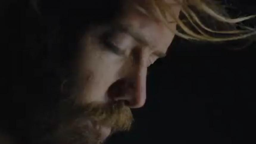A man stands with his head bowed and eyes closed as a bright light flashes on and off
