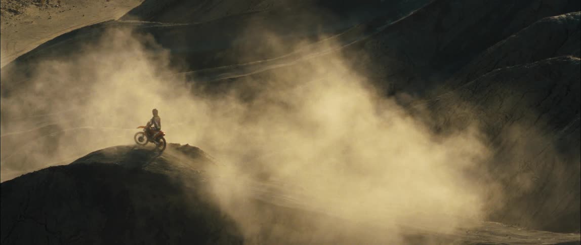 A man sits on his dirt bike on the sand dune
