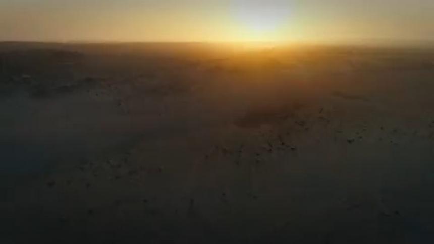 The low sun looms over a vast arid countryside