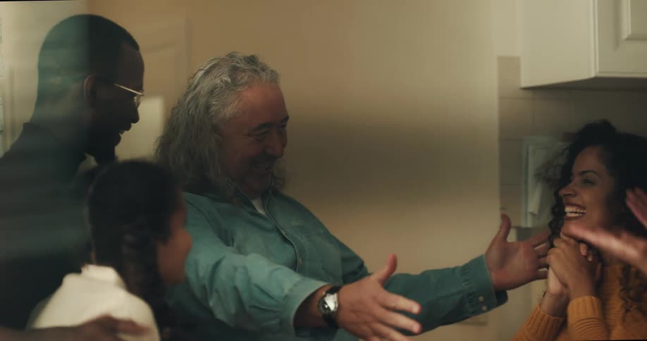 Man walks into room and greets people with hugs