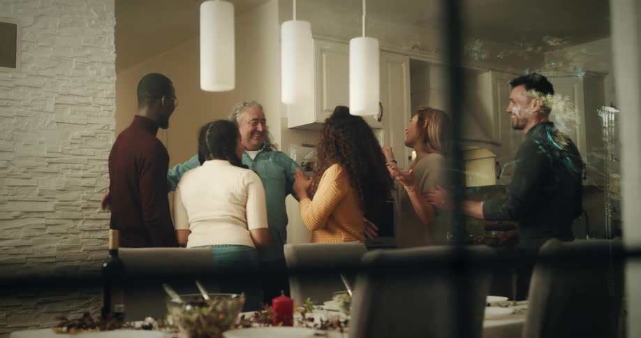 Group of happy friends greet each other with hugs on the dinning room at home