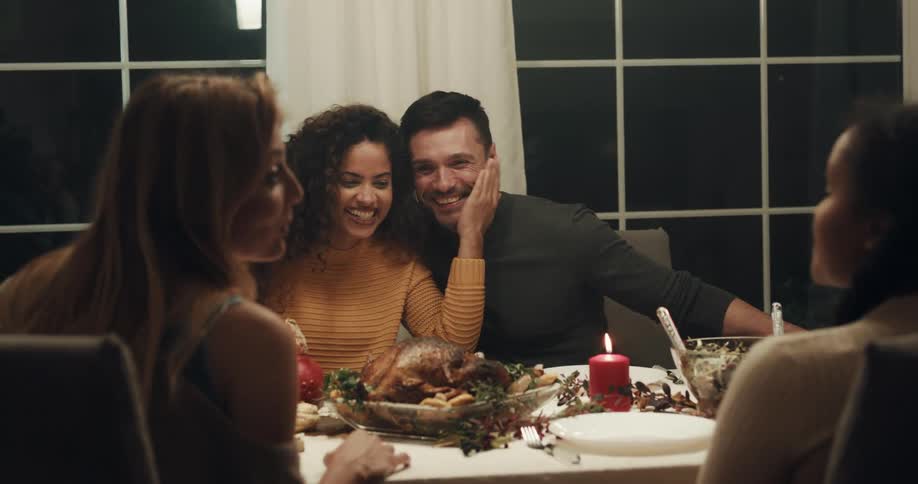 A man puts his arm around his girlfriend during a holiday dinner with friends