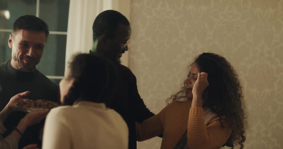 A family of three enters and greets their hosts with hugs and kisses and gifts