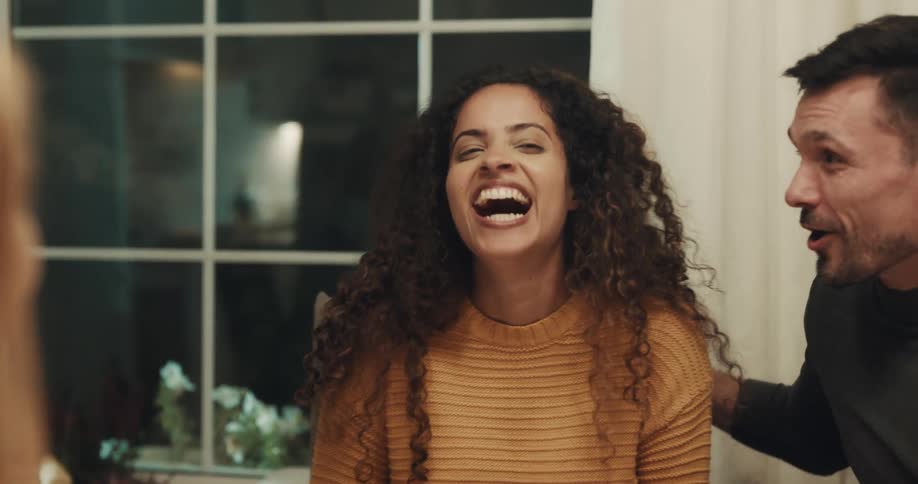 Friends sit around table near window laughing and talking