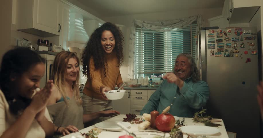 A family gathers around a dining table in a home kitchen