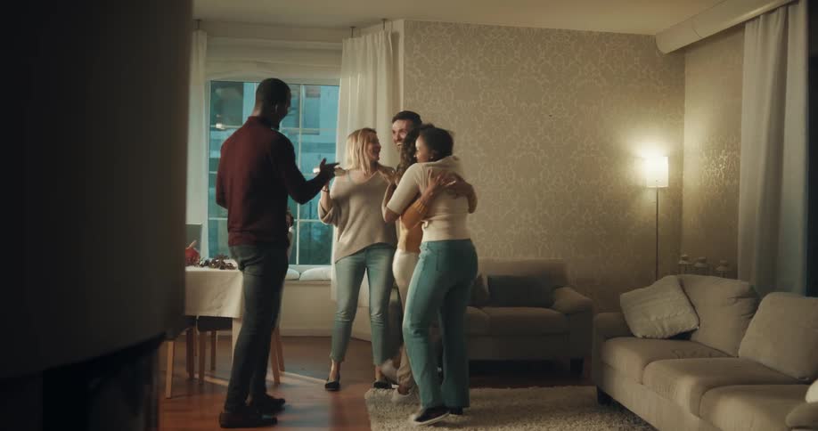 Young group of happy friends greet each other with hugs on the living room at home