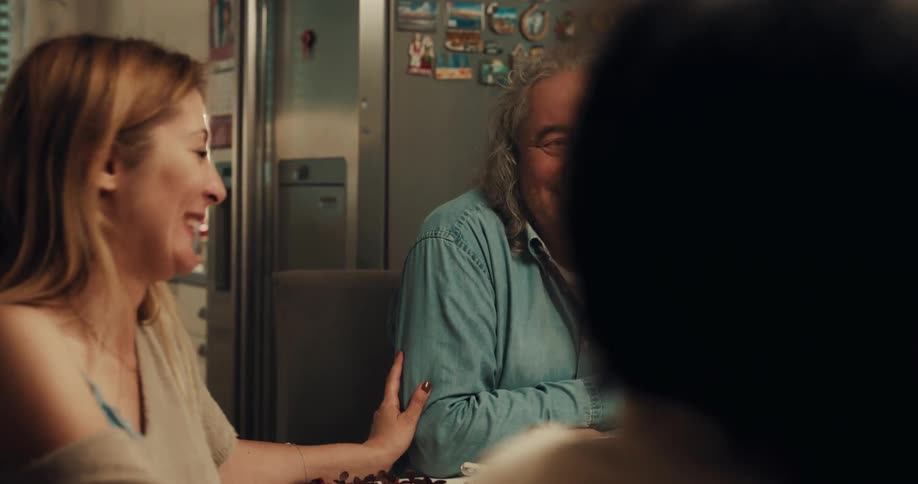 A family talks and laughs around a dinner table at night