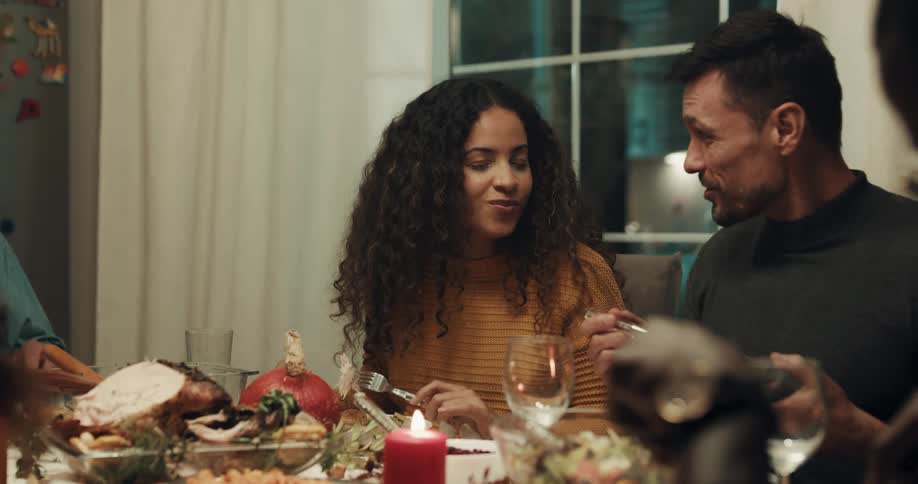 A group of friends pass food and eat turkey during a celebration