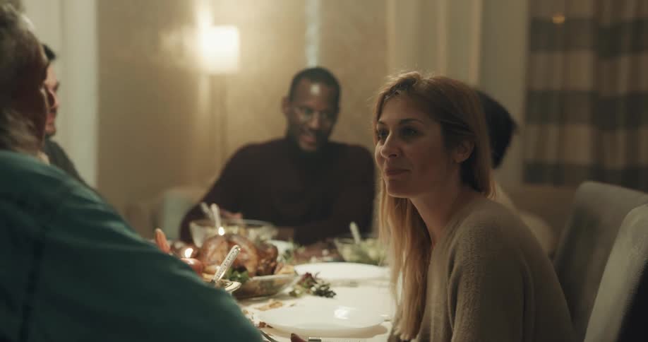Friends sit around dinner table laughing and talking