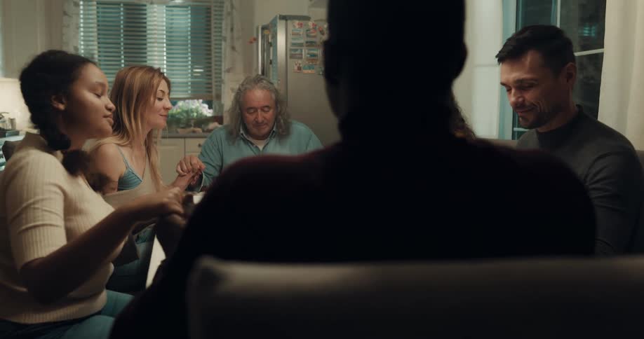 Friends gathered at the dinner table saying grace before eating