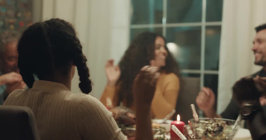 A woman says grace as she and friends hold hands in prayer before dinner