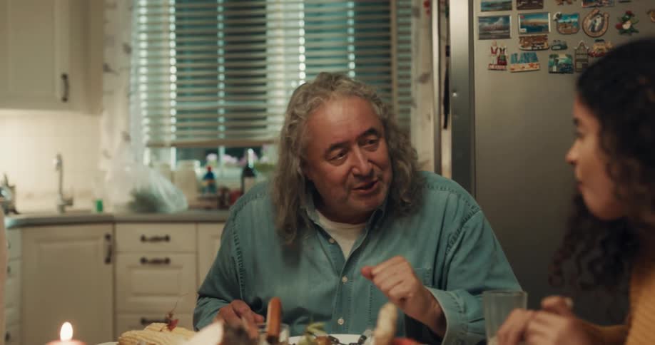 Family and friends pass around bowls of food while eating dinner at home