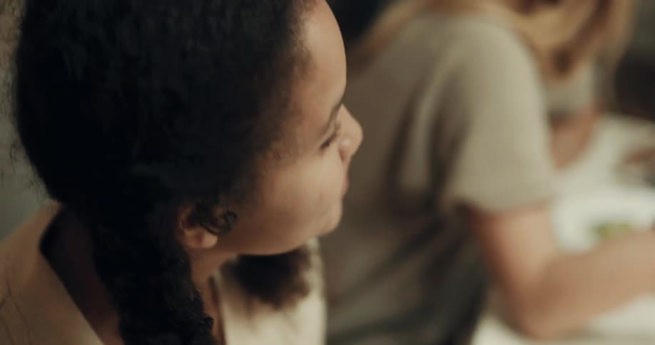 Teenage girl sits at dinner table with others singing