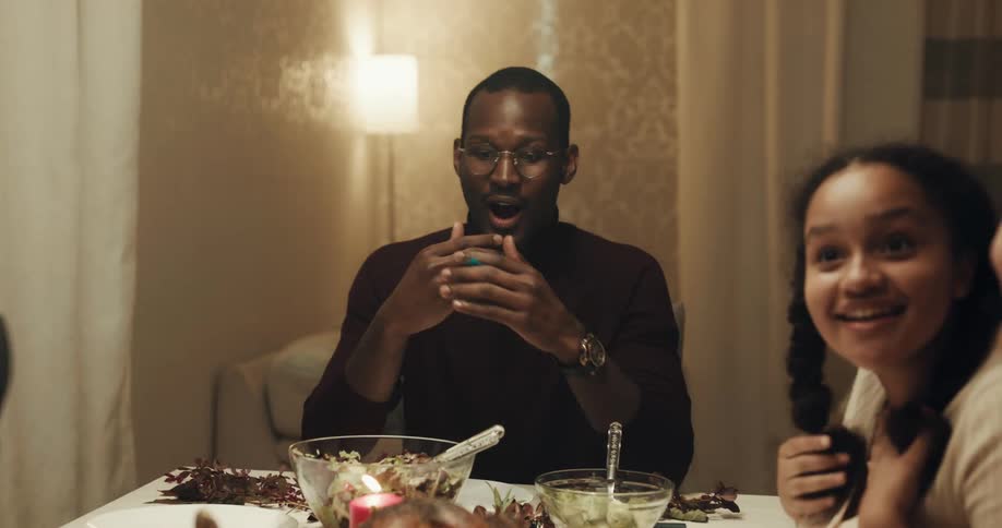 A group of friends cheer as a woman brings a turkey to their table