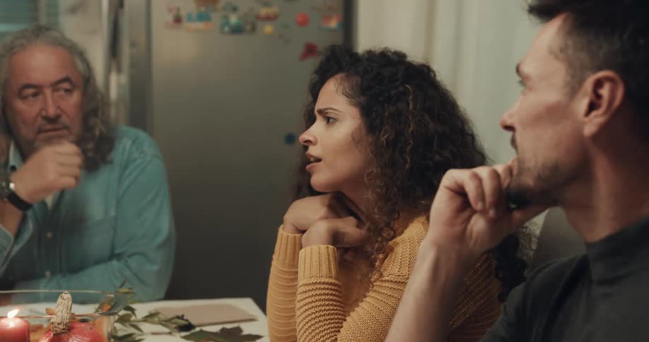 A young woman talks with her family as they sit around a kitchen table