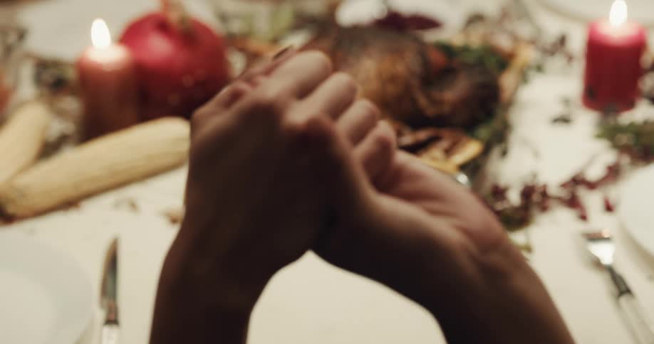People holding hands to say grace at the holiday dinner table