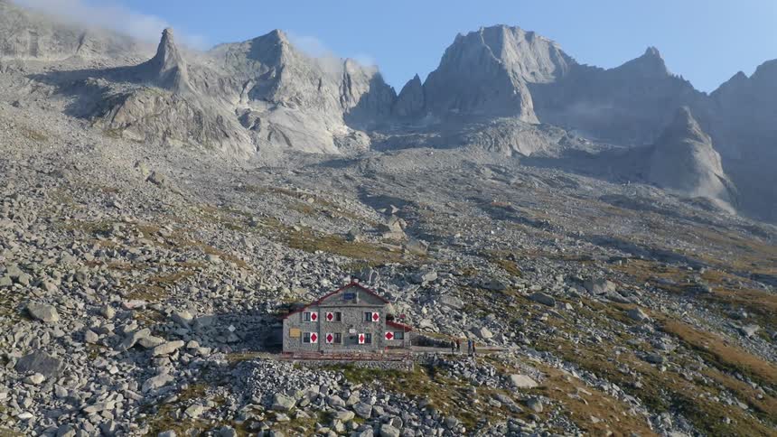 An aerial view of a remote building in tall mountains in the daytime