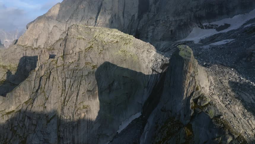 One small peak casts shadow on the side of the other as snow covers valley on incline of mountain