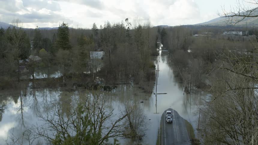 Flooded streets surround a small town as storm clouds loom overhead