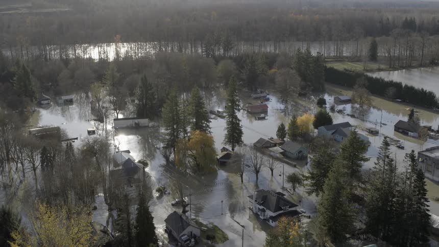 A car slowly makes its way through the silty water of a flooded neighborhood