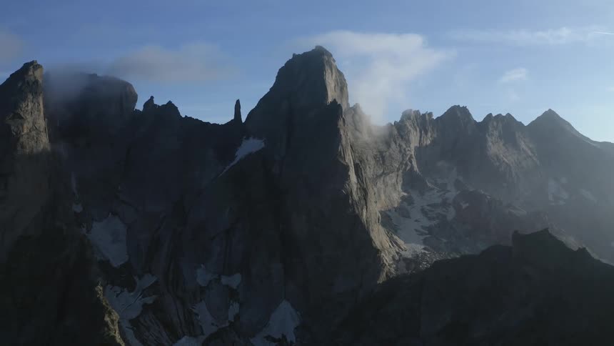 Clouds are hanging over rocky peaks on the ridge of a mountain