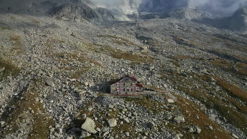 A lone building on a foggy mountain slope covered in rocks
