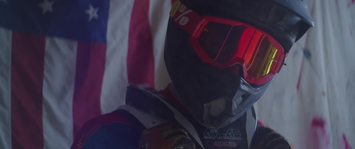 Person wearing helmet and goggles with american flag in the background