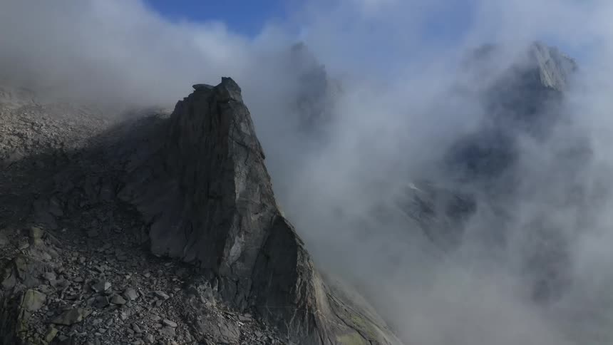 Clouds cover mountain tops and peaks high in the sky