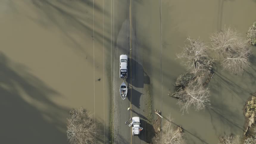 A FEMA crew prepares to launch a small boat into the murky water along a flooded road