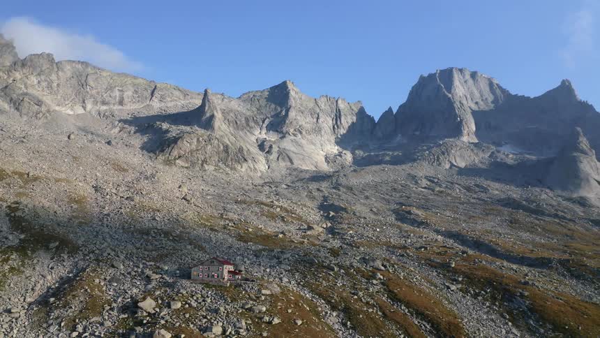 A lone building on a mountain slope covered in rocks on a clear day
