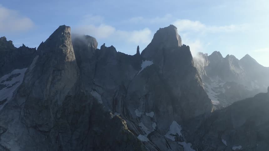 A jagged mountain ridge covered in patches of snow on a sunny day