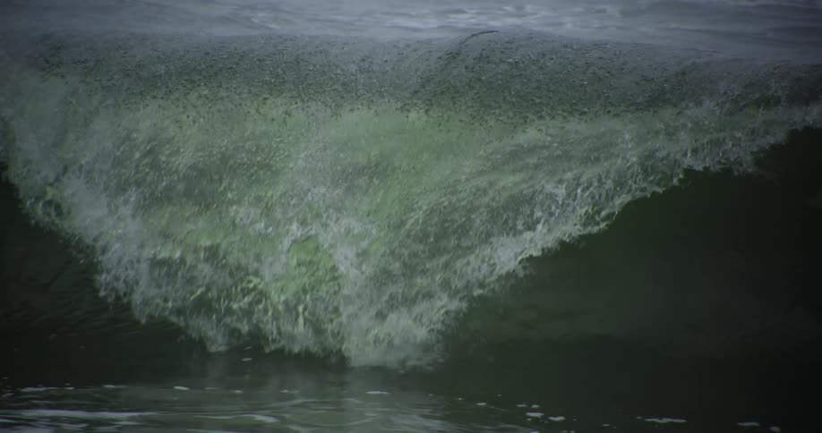 A large ocean wave is crashing over and splashing water