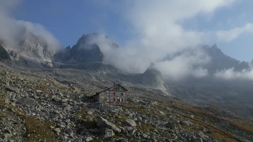 An aerial view of a remote buildings in tall mountains on a cloudy day