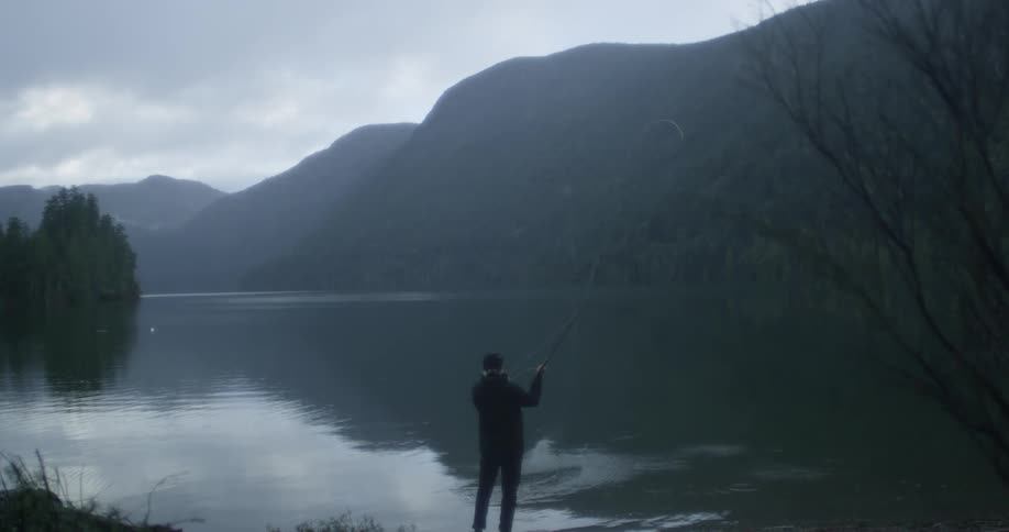 A man casts a long fishing line into a lake