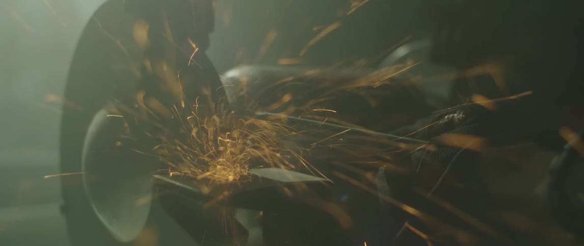 A person grinding some metal in a shop