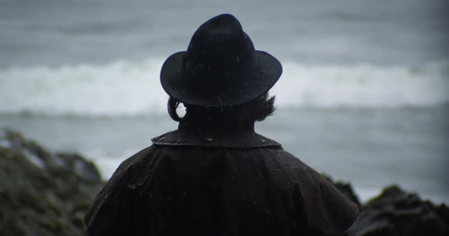 A woman is standing and looking out over the waves in the ocean
