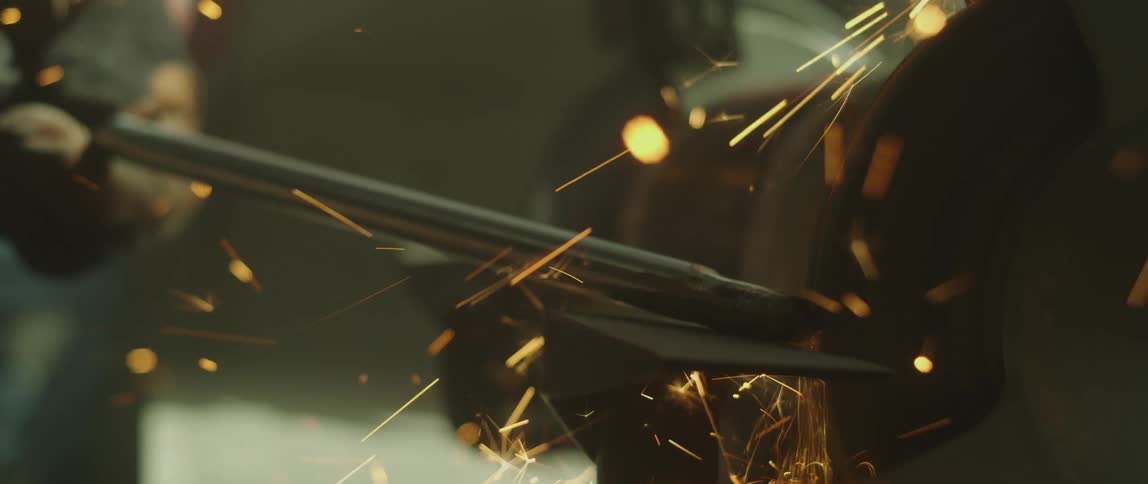 Sparks are flying as someone puts a piece of metal against a grinding wheel