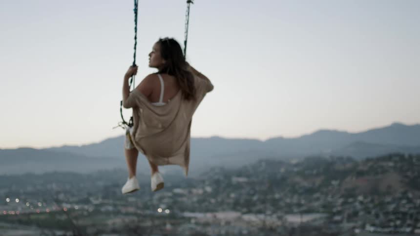 A woman in a brown dress swings on a swing
