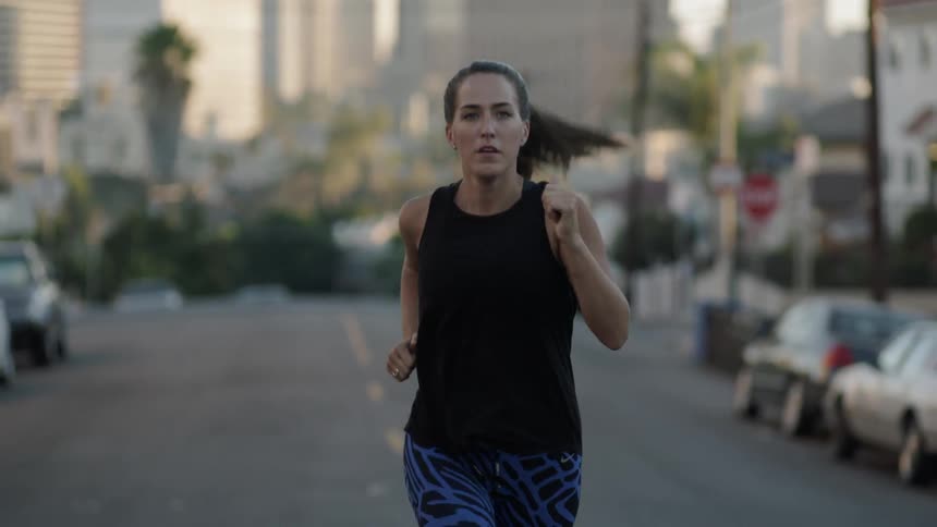 A woman runs in a street with her hair jumping up and down behind her