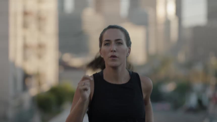 A woman is running with buildings behind her