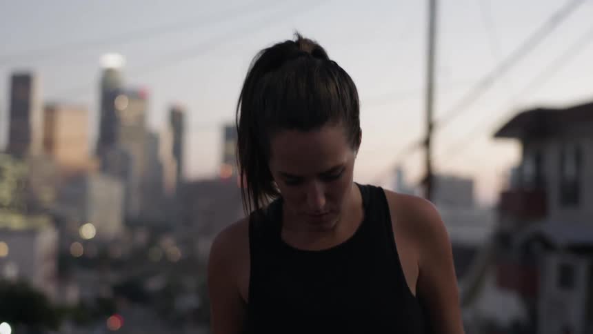 A woman is in the street looking down before a city