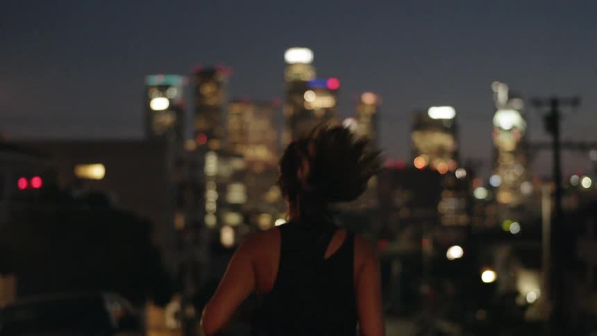 A woman jogs in a city at night