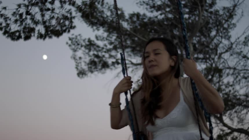 A woman swings near dusk