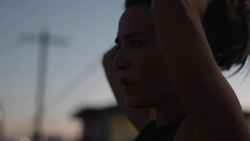 A woman pulls her hair back and ties it