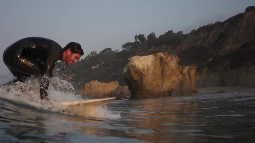 A man rides a wave in on his surfboard