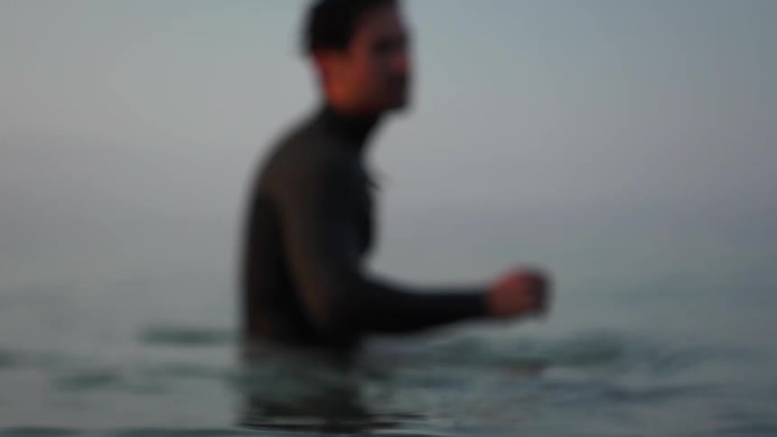 A man sits on a surfboard in a body of water