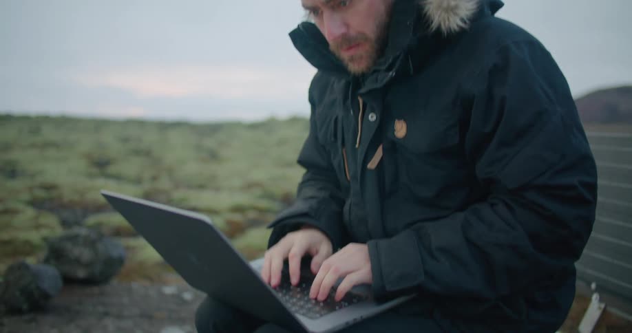 A man sitting outdoors using a laptop