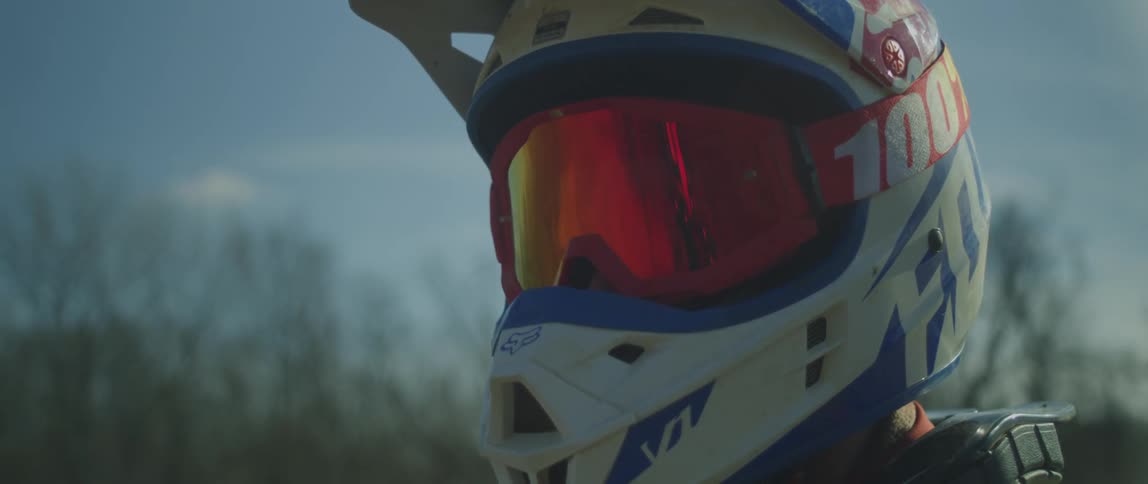 A person wearing a helmet is looking around outside near barren trees