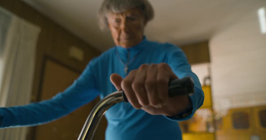 A woman places her hands on the handlebars of a bike indoors